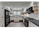 Modern kitchen with white cabinets, black appliances, subway tile, and dark countertops at 443 Lakeshore Dr, Berkeley Lake, GA 30096