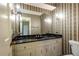 Compact bathroom featuring patterned wallpaper, vanity with a black countertop, and sconce lighting at 295 Glen Lake Dr, Atlanta, GA 30327