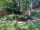 Private backyard featuring lush landscaping, grassy lawn, and a decorative fish pond at 3075 Nuthatch Nw Ct, Kennesaw, GA 30144