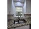 A kitchen sink and window with granite countertops, tile backsplash, and white cabinets at 3075 Nuthatch Nw Ct, Kennesaw, GA 30144