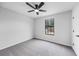 An empty bedroom with freshly painted gray walls, gray carpet, and a ceiling fan with light and one window at 2246 Hightrail Ct, Lithonia, GA 30058