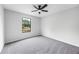 An empty bedroom with freshly painted gray walls, gray carpet, and a ceiling fan with light and one window at 2246 Hightrail Ct, Lithonia, GA 30058