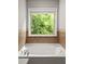A bathtub with tile surround, featuring a window that provides natural light and a view of the outdoors at 732 Province Se Pl, Atlanta, GA 30312