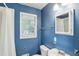 Blue-walled bathroom features a vanity, a toilet, a shower with a curtain, and a window at 1426 Diamond Head Dr, Decatur, GA 30033