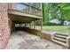 View of the home's brick patio underneath a deck with retaining wall and stairs at 1426 Diamond Head Dr, Decatur, GA 30033