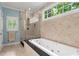 Bathroom featuring a glass-enclosed shower, soaking tub, and window letting in natural light at 2140 Azalea Dr, Roswell, GA 30075