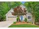 Charming exterior of home featuring a manicured lawn, blue front door, and lush landscaping at 1405 Arden Trace Ln, Lawrenceville, GA 30043