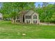 Charming two-story home with a lush green lawn, mature trees, and traditional architectural details at 3850 Pilgrim Mill Rd, Cumming, GA 30041