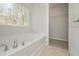 Bathroom featuring a garden tub, a door to the walk-in closet, and a view of the outdoors at 500 Charleston Pl, Villa Rica, GA 30180