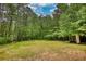 Large backyard with lawn surrounded by woods, with small structure on the edge at 547 Ellington Rd, Oxford, GA 30054
