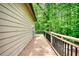 Deck overlooking a wooded yard with metal railings and an adjacent home wall at 547 Ellington Rd, Oxford, GA 30054