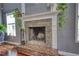 Close-up of the stone fireplace with plants and natural light from the windows at 547 Ellington Rd, Oxford, GA 30054