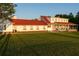 Expansive white farmhouse with a red roof, offering charm and curb appeal against a lush green lawn at 4076 Airline, Mcdonough, GA 30252