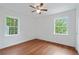 Bright bedroom with hardwood floors, a ceiling fan, and two windows showcasing the lush, green surroundings at 472 Rigby Ne St, Marietta, GA 30060