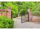 Charming gated entrance with brick pillars, a black metal gate, and green surroundings at 3845 Parian Nw Rdg, Atlanta, GA 30327
