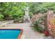 Inviting pool area with a stone fireplace feature, mature plants, and brick accents at 3845 Parian Nw Rdg, Atlanta, GA 30327