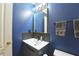 Stylish bathroom with blue walls, unique mirror, and modern vanity provides a luxurious feel at 589 Fox Creek Xing, Woodstock, GA 30188