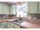 Bright kitchen showcasing a stainless steel sink, butcher block countertop, and unique backsplash at 589 Fox Creek Xing, Woodstock, GA 30188