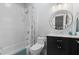 Well-lit bathroom with a shower-tub combo, black vanity with a white marble top, and circular mirror at 3265 Bentwood Close, Cumming, GA 30041