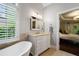 Well-lit bathroom with a soaking tub, shuttered window, and marble countertop at 3265 Bentwood Close, Cumming, GA 30041