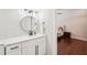 Well-lit bathroom vanity with modern fixtures, white cabinets, round mirror, and a glimpse into an adjacent bedroom at 3851 Glenhurst Se Dr, Smyrna, GA 30080