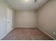 Bedroom with light walls, tan carpet, bright light fixture and a door at 6351 Stablewood Way, Lithonia, GA 30058