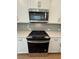 Close up of stove and microwave, white cabinets, and tiled backsplash at 1932 Appian Aly, Kennesaw, GA 30144