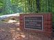 Kennesaw Mountain National Battlefield Park sign with brick base and surrounding woods and road at 1932 Appian Aly, Kennesaw, GA 30144
