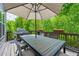 Outdoor deck with dining table, grill, and a large shade umbrella surrounded by trees at 3755 Valleyway Rd, Cumming, GA 30040