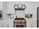 Close-up of the kitchen's stainless steel range with red knobs and modern vent hood at 3755 Valleyway Rd, Cumming, GA 30040