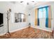 Bedroom featuring wood floors, a large window with curtains, and an accent mirror on the wall at 3140 Willow Park Dr, Dacula, GA 30019
