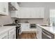 Bright modern kitchen with white cabinets, stainless steel appliances, and granite countertops at 613 Stickley Oak Way, Woodstock, GA 30189