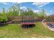 Landscaped backyard featuring a trampoline, terraced garden beds, and a well-maintained lawn at 7730 Tiberon Pkwy, Cumming, GA 30028