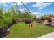 Expansive backyard with a trampoline, a swing, a playset, and landscaped garden beds under a blue sky at 7730 Tiberon Pkwy, Cumming, GA 30028