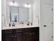 Bathroom featuring double sink vanity with dark wood cabinets, large mirror, and stylish fixtures at 7730 Tiberon Pkwy, Cumming, GA 30028