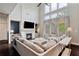 Bright living room with a fireplace, large sectional sofa, high ceilings, and expansive windows at 7730 Tiberon Pkwy, Cumming, GA 30028