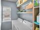 Bright laundry room features a white washer and dryer, with shelf storage above and a window to the left at 3162 Citrus Ct, Decatur, GA 30034