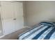 Bedroom featuring neutral walls, a blue and gray bedspread, and double closet doors at 243 Beau St, Lilburn, GA 30047