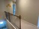 Hallway staircase with neutral walls, neutral carpet, and black iron railing at 243 Beau St, Lilburn, GA 30047