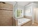 Modern bathroom featuring a glass enclosed shower, large tub, and a window with shutters at 1446 Wilford Ne Dr, Atlanta, GA 30319