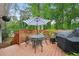 Outdoor deck with a table, chairs, umbrella, grill, and a view of the wooded backyard at 2193 Cloverdale Se Dr, Atlanta, GA 30316