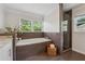 Bright bathroom featuring a soaking tub beneath a window and a glass-enclosed shower at 3772 Evans Rd, Atlanta, GA 30340
