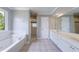 Bright bathroom featuring a tub with a window, walk-in shower, tile floors, and dual sink vanity at 1523 Fallen Leaf Dr, Marietta, GA 30064