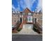 Brick townhome featuring an attached garage and well-maintained front yard landscaping at 6121 Joybrook Rd, Johns Creek, GA 30097