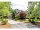 Brick and stone home boasts a manicured lawn, mature trees, and a side-entry three car garage at 1575 Spalding Dr, Sandy Springs, GA 30350