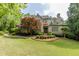 Charming brick home featuring a manicured lawn, mature trees, and classic architectural details at 1575 Spalding Dr, Sandy Springs, GA 30350