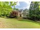 Charming brick home featuring a manicured lawn, mature trees, and classic architectural details at 1575 Spalding Dr, Sandy Springs, GA 30350