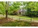 Charming brick home featuring a manicured lawn, mature trees, and classic architectural details at 1575 Spalding Dr, Sandy Springs, GA 30350