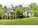 Rear exterior view of a two-story home featuring a balcony, brick accents, and a spacious, lush backyard at 1575 Spalding Dr, Sandy Springs, GA 30350
