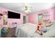 Cozy pink bedroom with TV, toys, and an open doorway to an adjacent room at 209 Braemar Ct, Mcdonough, GA 30253